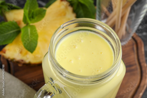 Tasty pineapple smoothie in mason jar on table, closeup