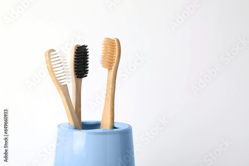 Bamboo toothbrushes in holder on white background, space for text