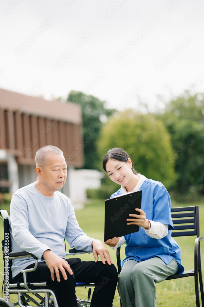 Elderly asian senior man on wheelchair with Asian careful caregiver and encourage patient, walking in garden. with care from a caregiver and senior health insurance.. Elderly asian senior man on wheelchair with Asian careful caregiver and encourage patient, walking in garden. with care from a caregiver and senior health insurance..