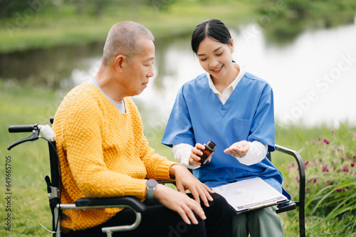 Elderly asian senior man on wheelchair with Asian careful caregiver. Nursing home hospital garden concept.