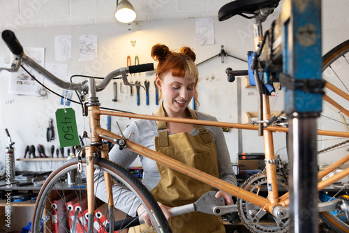 Young adult female repairing a bicycle in a bike store