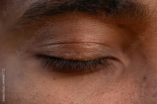 Close-up of a closed eye of a young African man, black lashes, detailed skin texture photo