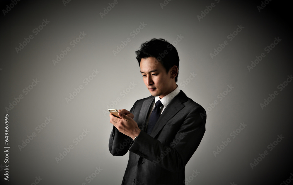携帯を持つスーツを着た日本人ビジネスマン 携帯を持つスーツを着た日本人ビジネスマン