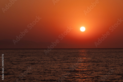 Alba dal mare con sole che sorge cielo con luce calda  arancio photo