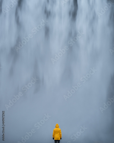 Mężczyzna stoi na tle wodospadu Skogafoss, Islandia