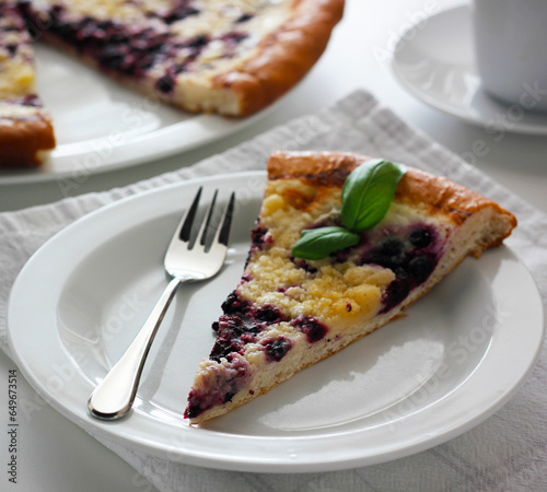 Piece of traditional Wallachian blueberry pie called "frgal" on a white plate. Traditional Moravian sweet dessert on white table. Typical Czech cuisine concept. Summer fruit cake.