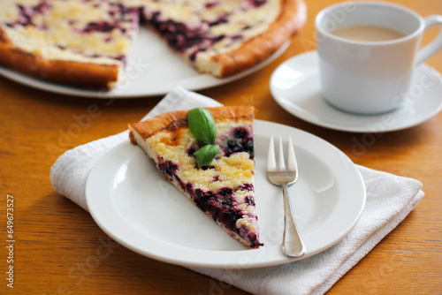 Piece of traditional Wallachian blueberry pie called "frgal" on a white plate. Traditional Moravian sweet dessert on wooden table. Typical Czech cuisine concept. Summer fruit cake. Selective focus.