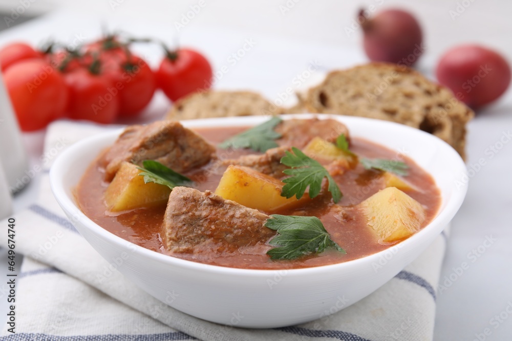 Delicious goulash in bowl on white table, closeup Delicious goulash in bowl on white table, closeup