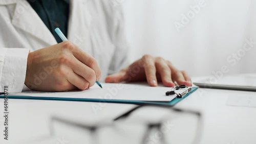 Patient. A male doctor in doctor's clothes works competently at a table in the waiting room. Close-up of a clinic worker specialist writing data information advanced diagnostic methods, medical care photo