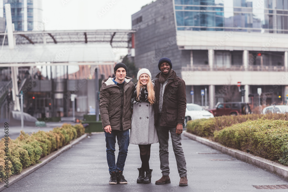 three young friends posing together in the street looking camera smiling three young friends posing together in the street looking camera smiling
