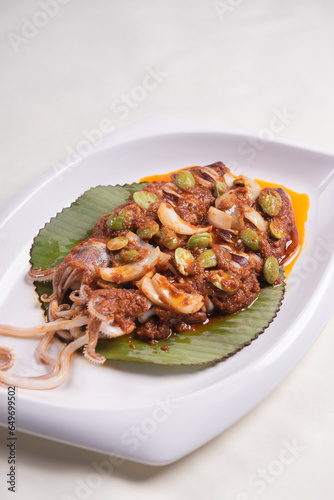 grilled bbq fresh whole seafood squid sooting octopus with spicy samba chilli sauce and petai smelly bean vegetables in banana leaf plate on wood table asian restaurant banquet cuisine halal food menu