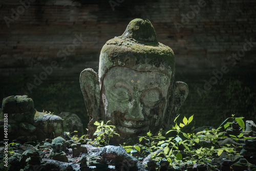 Ancient old ruins The Head of Buddha statue carved from sandstone was destroyed and abandoned left in the Wat UMong Temple. The travel destination temple in Chiang Mai, Thailand. photo