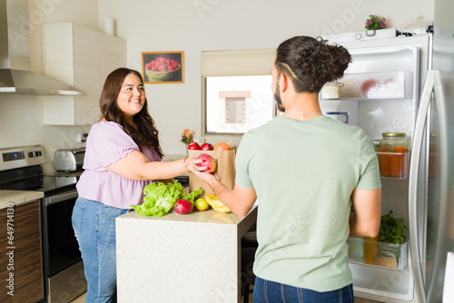 Cheerful couple in the kitchen with the open fridge
