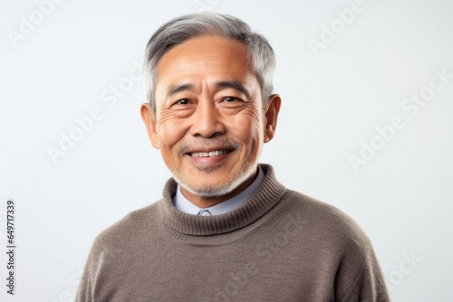 portrait of a confident Filipino man in his 60s wearing a chic cardigan against a white background © Robert MEYNER
