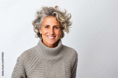 portrait of a confident Israeli woman in her 50s wearing a cozy sweater against a white background