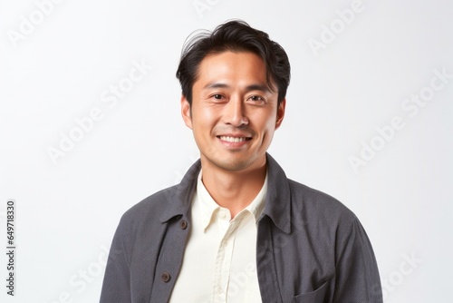 portrait of a confident Japanese man in his 30s wearing a chic cardigan against a white background