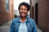 Portrait of a happy Kenyan woman in her 30s wearing a denim jacket against a minimalist or empty room background