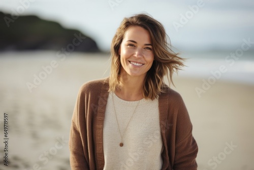 Portrait of a happy Polish woman in her 30s wearing a chic cardigan against a beach background