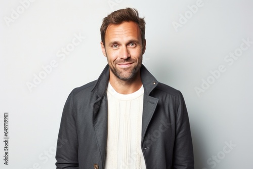 portrait of a confident Polish man in his 30s wearing a chic cardigan against a white background