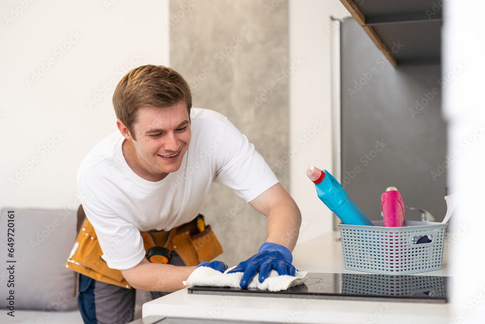 young cheerful man cleaning kitchen dirty household duty spray bottle dust indoors young cheerful man cleaning kitchen dirty household duty spray bottle dust indoors