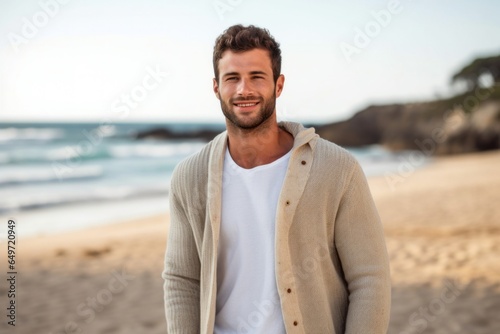 portrait of a Israeli man in his 20s wearing a chic cardigan against a beach background