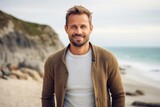 Portrait of a Polish man in his 30s wearing a chic cardigan against a beach background