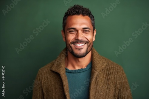 medium shot portrait of a confident Mexican man in his 30s wearing a chic cardigan against an abstract background