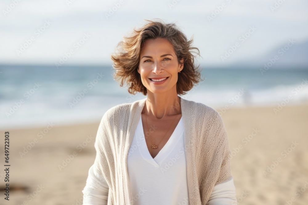 Portrait of a confident Israeli woman in her 50s wearing a chic cardigan against a beach background Portrait of a confident Israeli woman in her 50s wearing a chic cardigan against a beach background