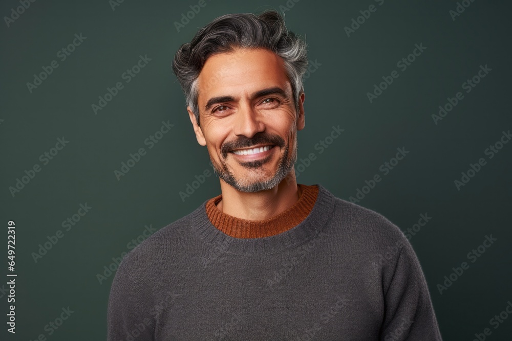medium shot portrait of a confident Mexican man in his 40s wearing a cozy sweater against an abstract background