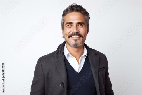 Portrait of a serious, Mexican man in his 40s wearing a chic cardigan against a white background