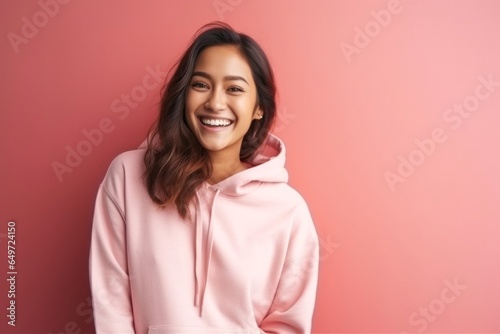 medium shot portrait of a happy Filipino woman in her 20s wearing a stylish hoodie against an abstract background
