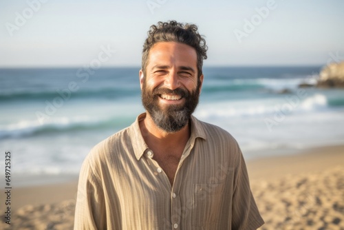medium shot portrait of a happy Israeli man in his 40s wearing a chic cardigan against a beach background