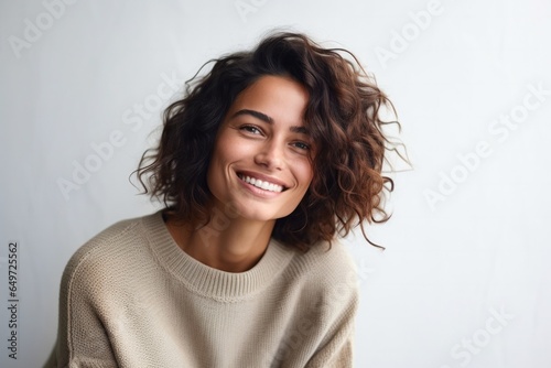 medium shot portrait of a happy Israeli woman in her 30s wearing a cozy sweater against a minimalist or empty room background