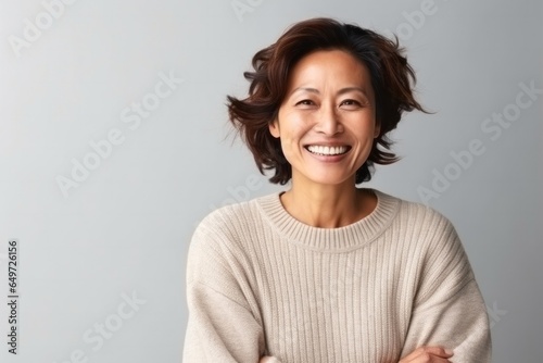 medium shot portrait of a happy Japanese woman in her 40s wearing a cozy sweater against a minimalist or empty room background