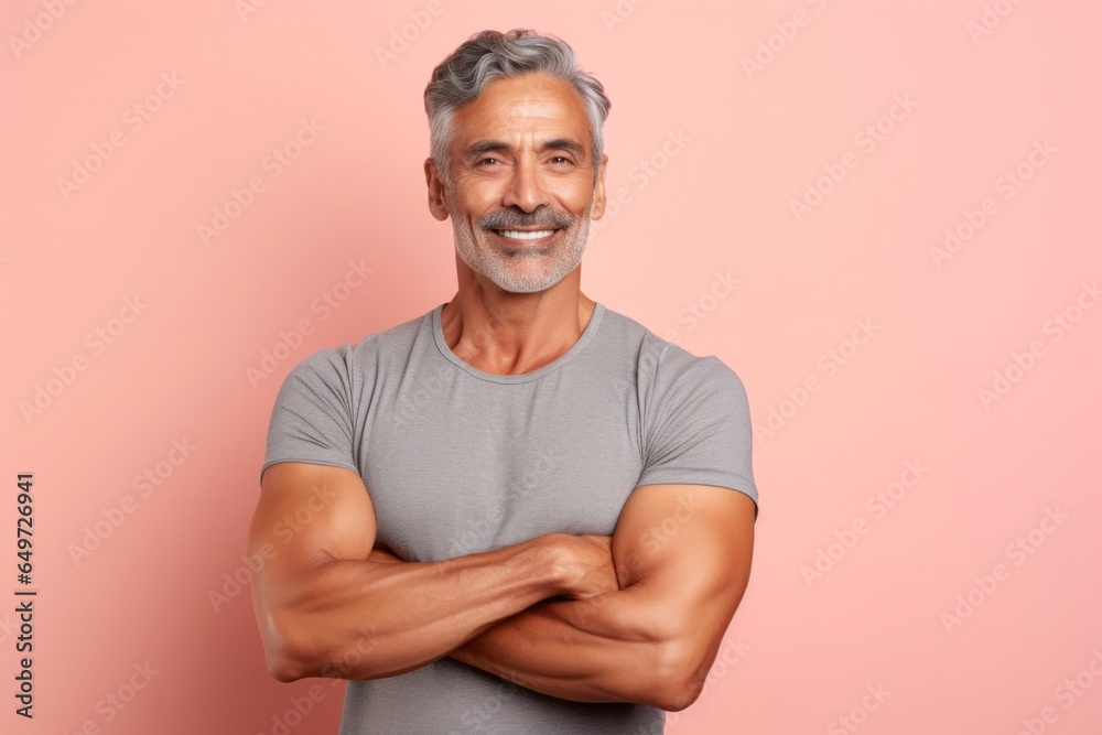 medium shot portrait of a happy Mexican man in his 50s wearing a sporty tank top against a pastel or soft colors background medium shot portrait of a happy Mexican man in his 50s wearing a sporty tank top against a pastel or soft colors background