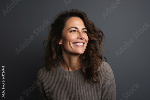 portrait of a happy Israeli woman in her 40s wearing a cozy sweater against a minimalist or empty room background