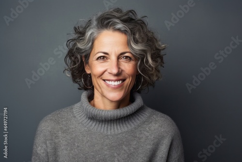 portrait of a happy Israeli woman in her 50s wearing a cozy sweater against an abstract background