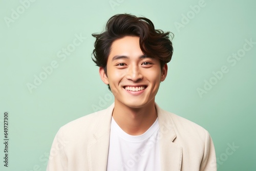 portrait of a happy Japanese man in his 20s wearing a chic cardigan against a pastel or soft colors background