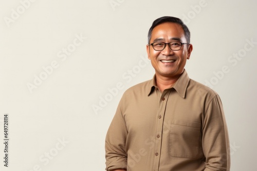 medium shot portrait of a Filipino man in his 50s wearing a chic cardigan against a minimalist or empty room background