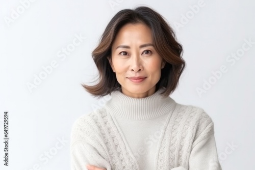 medium shot portrait of a Japanese woman in her 40s wearing a cozy sweater against a white background © Anne-Marie Albrecht