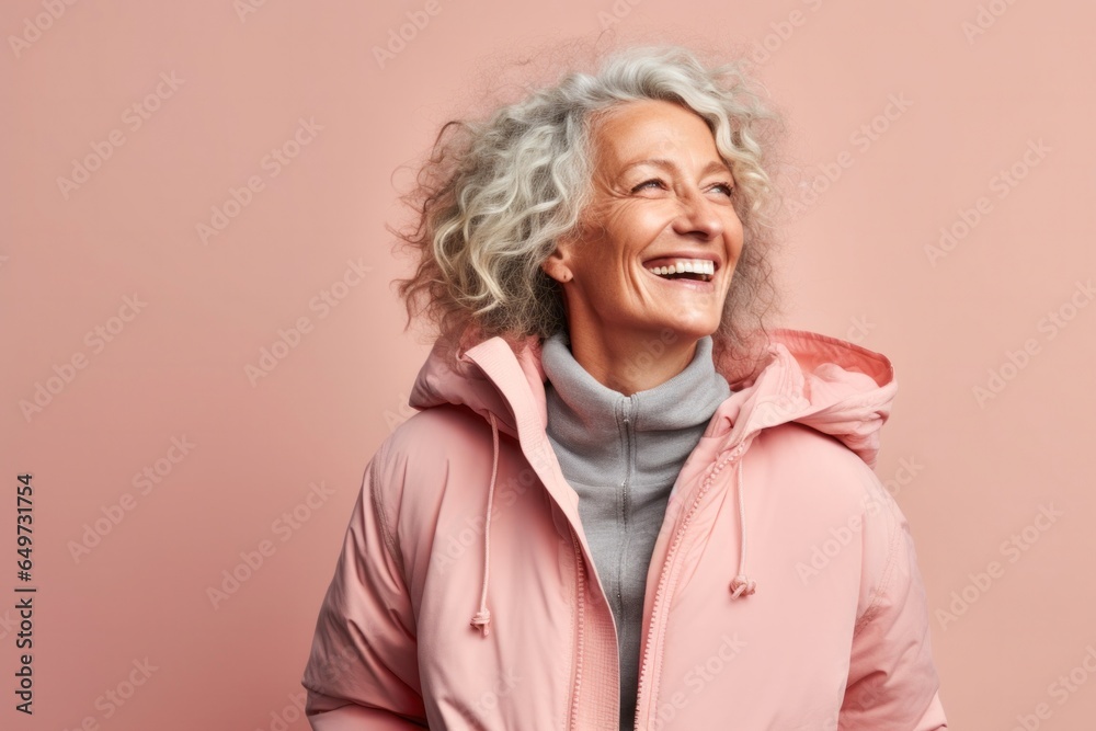 portrait of a Israeli woman in her 50s wearing a warm parka against a pastel or soft colors background portrait of a Israeli woman in her 50s wearing a warm parka against a pastel or soft colors background