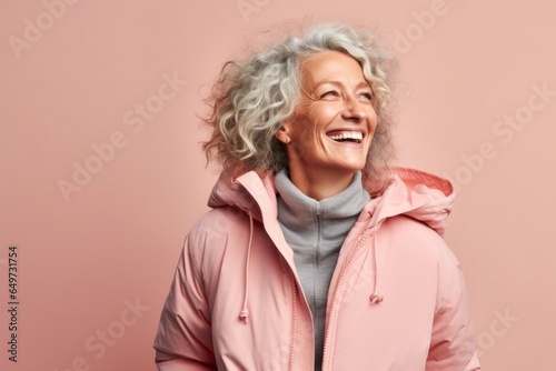 portrait of a Israeli woman in her 50s wearing a warm parka against a pastel or soft colors background © Leon Waltz