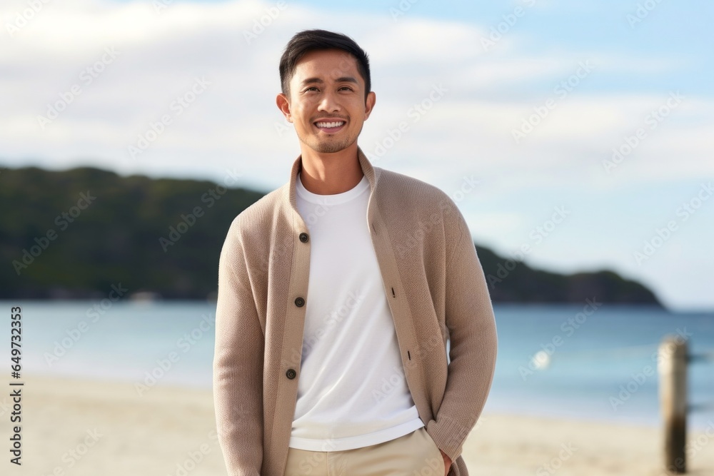 medium shot portrait of a confident Filipino man in his 30s wearing a chic cardigan against a beach background medium shot portrait of a confident Filipino man in his 30s wearing a chic cardigan against a beach background