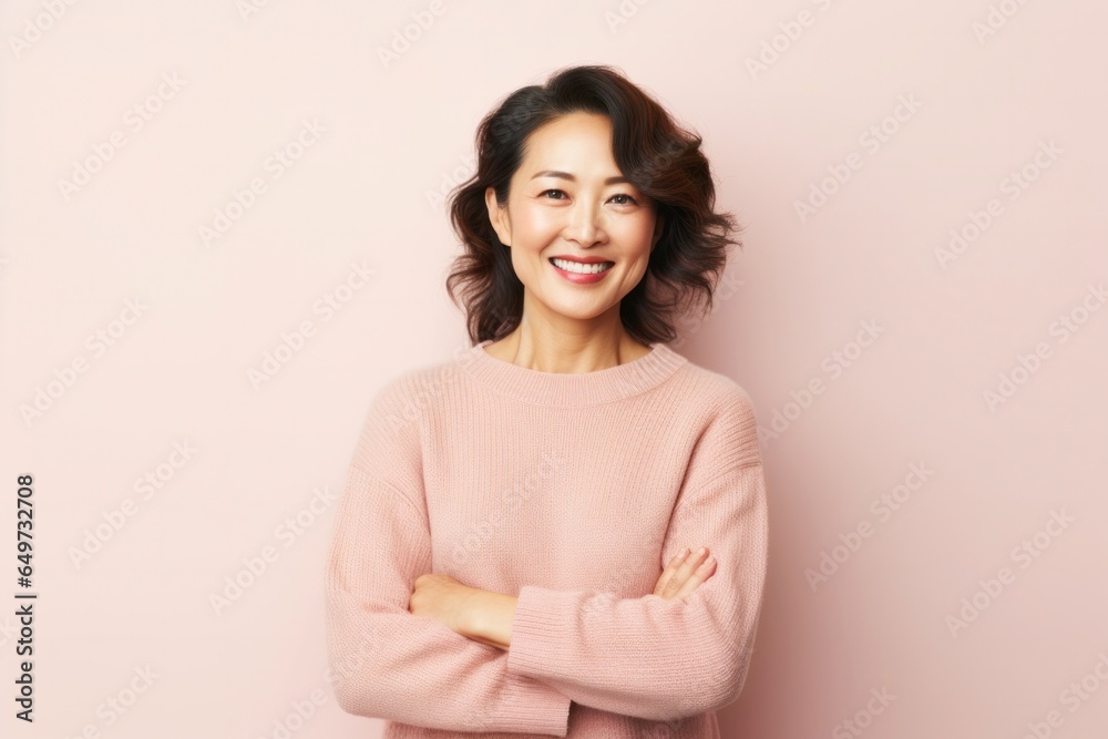 Fototapeta premium portrait of a Japanese woman in her 40s wearing a cozy sweater against a pastel or soft colors background