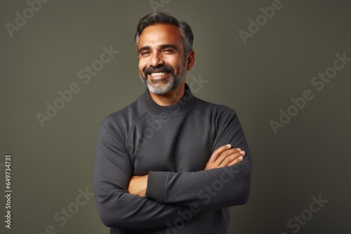 portrait of a Mexican man in his 50s wearing a chic cardigan against a minimalist or empty room background