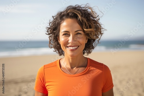 portrait of a Mexican woman in her 40s wearing a sporty polo shirt against a beach background © Leon Waltz