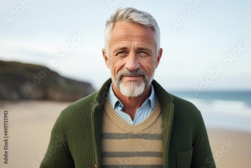portrait of a Polish man in his 50s wearing a chic cardigan against a beach background