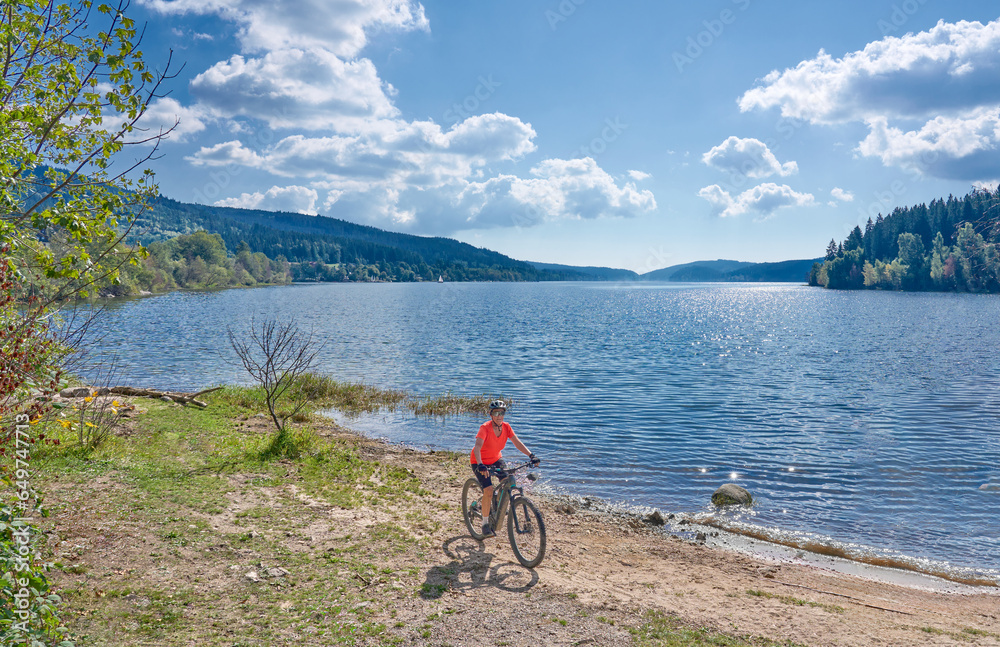 nice senior woman on her electric mountain bike cycling at Lake Schluchsee in the German Black Forest near Titisee-Neustadt, Baden-Württemberg, Germany
