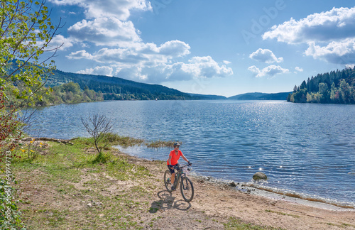 nice senior woman on her electric mountain bike cycling at Lake Schluchsee in the German Black Forest near Titisee-Neustadt, Baden-Württemberg, Germany 