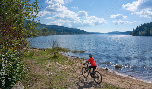 nice senior woman on her electric mountain bike cycling at Lake Schluchsee in the German Black Forest near Titisee-Neustadt, Baden-Württemberg, Germany 